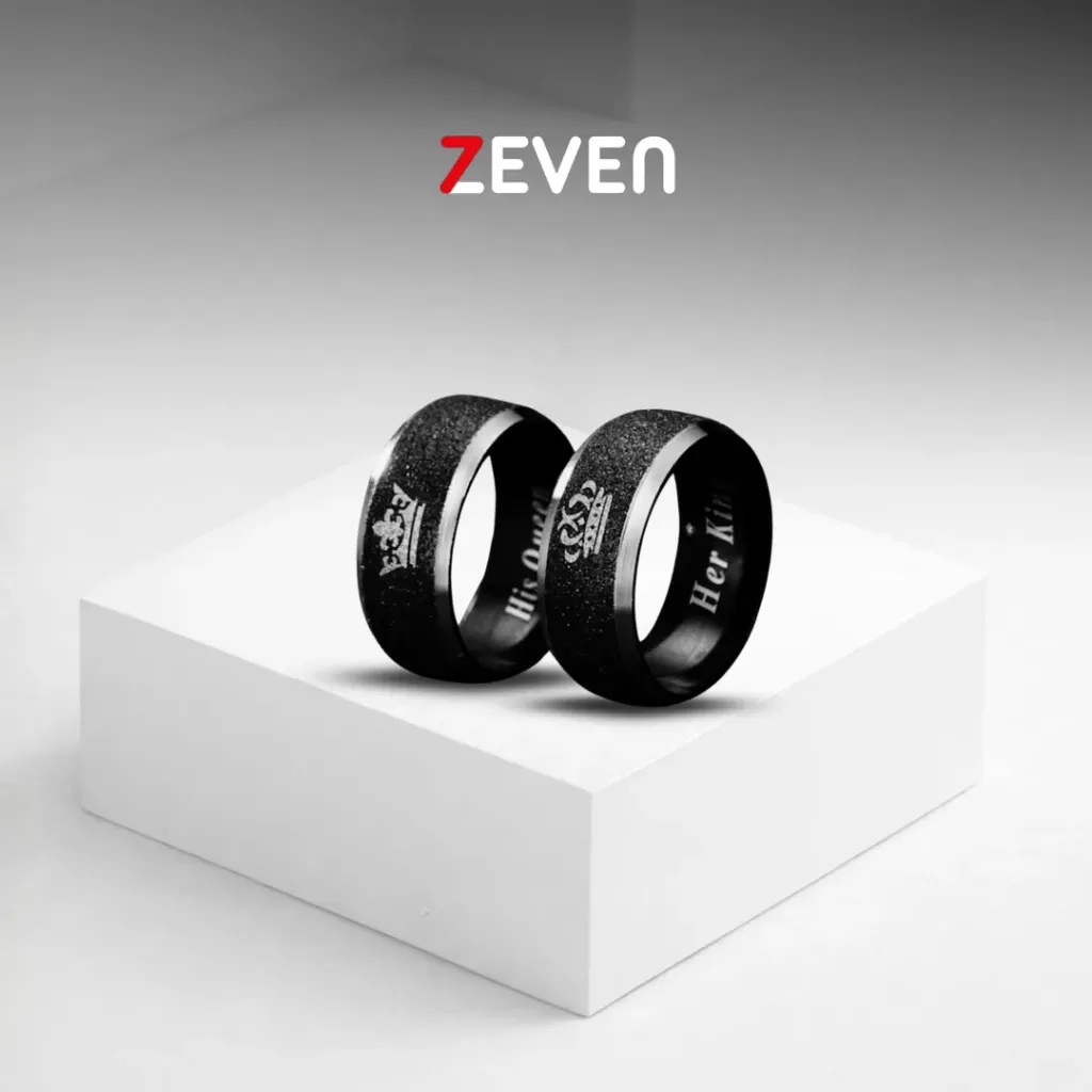 Set de dos anillos plateados con linea negra texturizada en el centro, con el grabado de "His Queen" y "Her King" dentro del anillo.