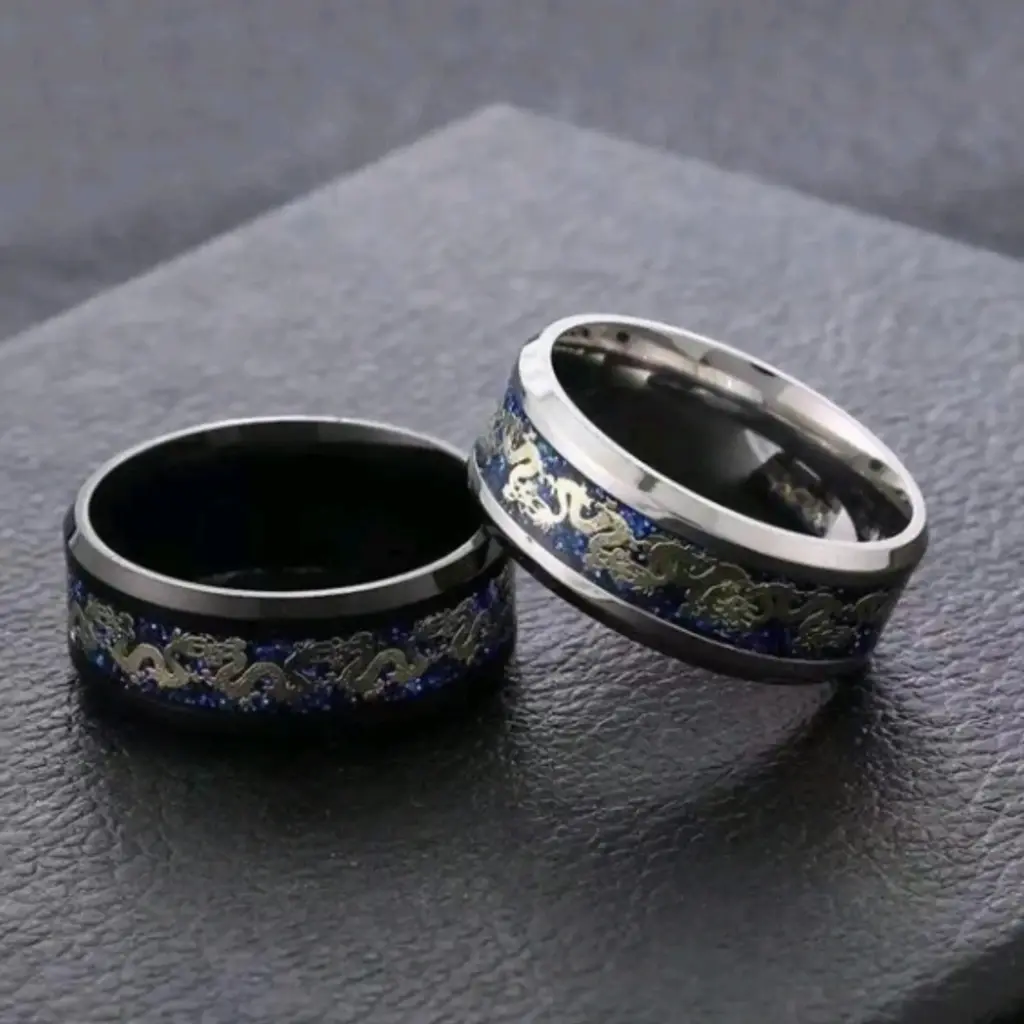 Set de dos anillos (uno plateado y uno negro) con una linea en el centro y detalle de un dragon en el centro.